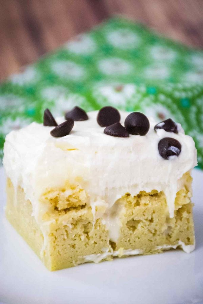 Keto Cannoli Poke Cake on a white plate with a green flowered napkin in the background